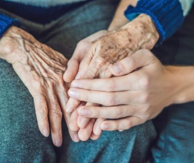 A child holds the hands of his old mother.